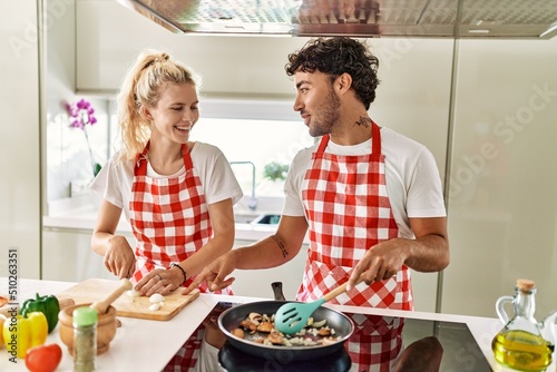Young couple smiling happy cooking using frying pan at kitchen.