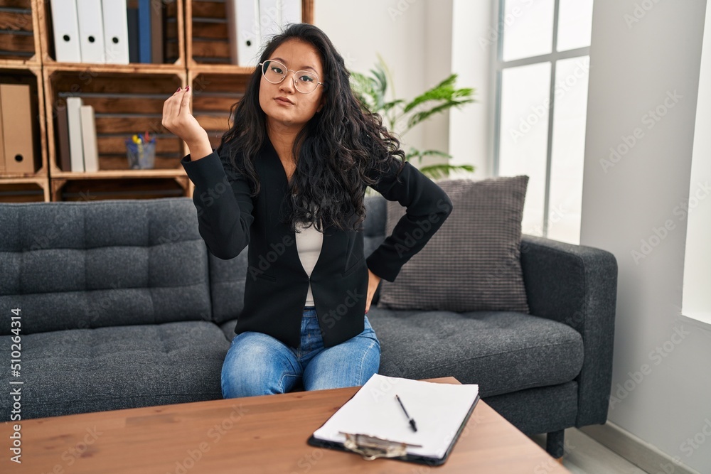 Young asian woman at consultation office doing italian gesture with hand and fingers confident expression