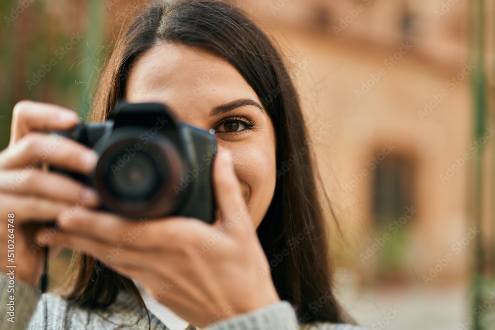 Young hispanic woman smiling happy using camera at the city.