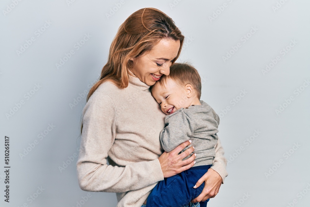 Young caucasian woman holding and hugging her son with love. Family of two bonding together. Mother holding infant toddler