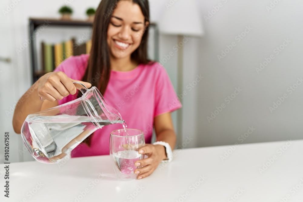 Young latin woman smiling confident pouring water at home Young latin woman smiling confident pouring water at home