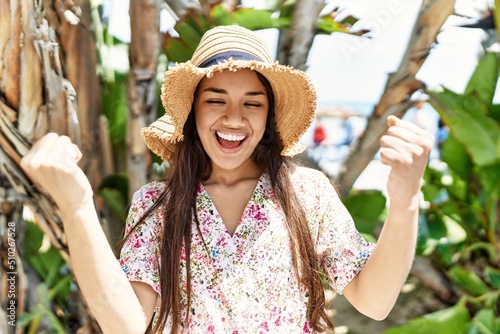 Young brunette woman outdoors on a sunny day of summer smiling happy pointing with hand and finger to the side photo