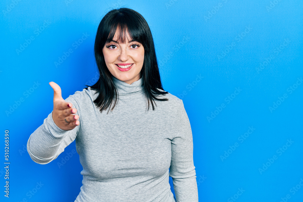 Young hispanic woman wearing casual clothes smiling friendly offering handshake as greeting and welcoming. successful business. Young hispanic woman wearing casual clothes smiling friendly offering handshake as greeting and welcoming. successful business.