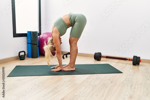 Young blonde girl concentrate training yoga at sport center.