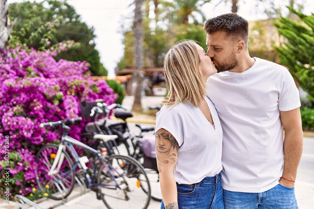 Young caucasian couple of boyfriend and girlfriend having fun outdoors on a un sunny day kissing in love Young caucasian couple of boyfriend and girlfriend having fun outdoors on a un sunny day kissing in love
