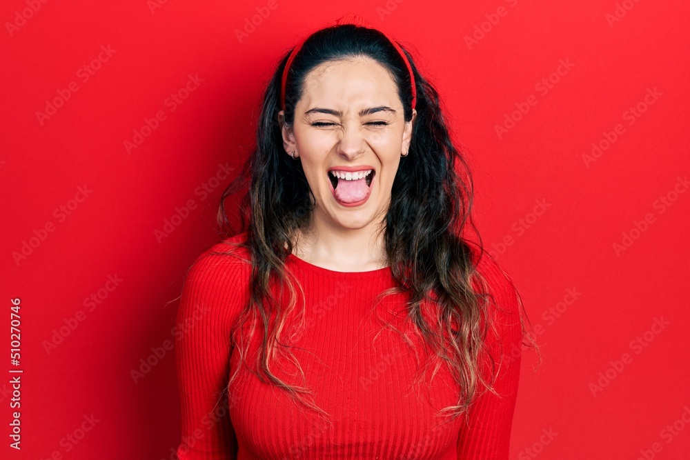 Young hispanic woman wearing casual clothes sticking tongue out happy with funny expression. emotion concept. Young hispanic woman wearing casual clothes sticking tongue out happy with funny expression. emotion concept.