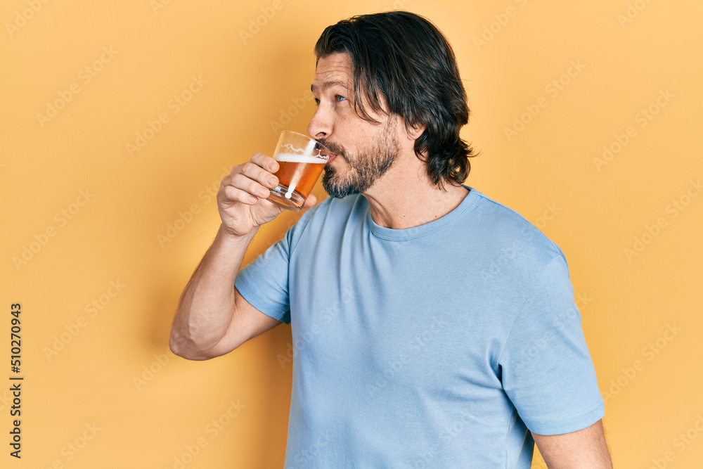 Middle age caucasian man with beard drinking a pint glass of fresh beer Middle age caucasian man with beard drinking a pint glass of fresh beer