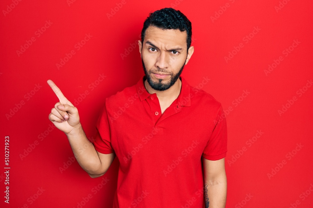Hispanic man with beard pointing with fingers to the side skeptic and nervous, frowning upset because of problem. negative person. Hispanic man with beard pointing with fingers to the side skeptic and nervous, frowning upset because of problem. negative person.
