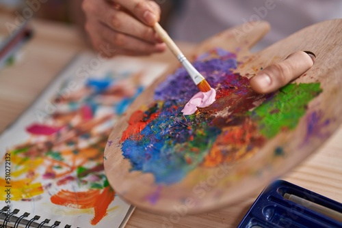 Young arab man mixing color on palette at art studio