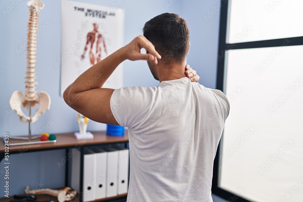 Fototapeta premium Young hispanic man injured physiotherapy patient suffering for neck ache at rehab clinic