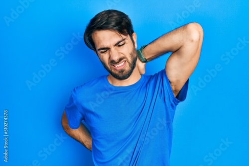 Young hispanic man wearing casual clothes suffering of neck ache injury, touching neck with hand, muscular pain