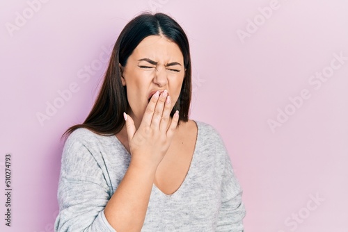 Young hispanic woman wearing casual clothes bored yawning tired covering mouth with hand. restless and sleepiness.