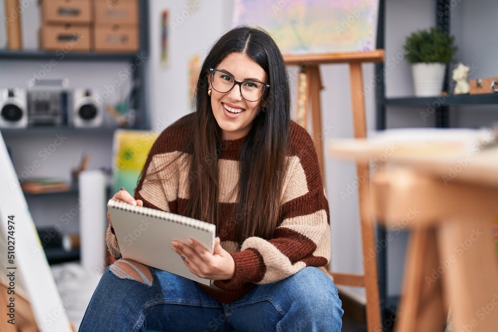 Young hispanic woman artist drawing on notebook at art studio Young hispanic woman artist drawing on notebook at art studio