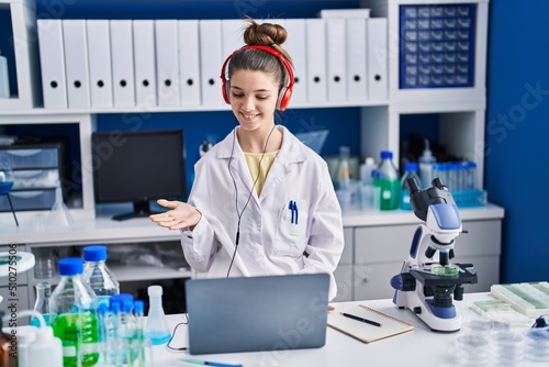 Teenager girl working at scientist laboratory celebrating achievement with happy smile and winner expression with raised hand