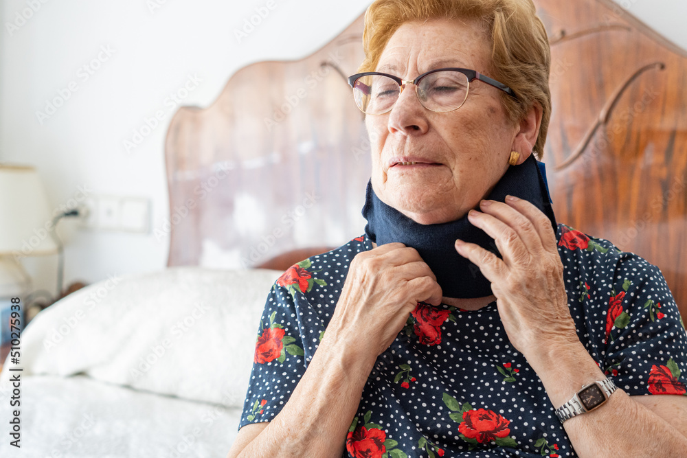 Portrait of elderly woman putting on a neck brace to improve neck pain