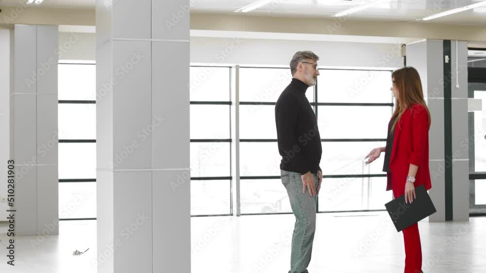 Unsuccessful negotiations, businessman, gray-haired man communicates with a woman in a red business suit, nods his head negatively and spreads his hands. The concept of failure Unsuccessful negotiations, businessman, gray-haired man communicates with a woman in a red business suit, nods his head negatively and spreads his hands. The concept of failure