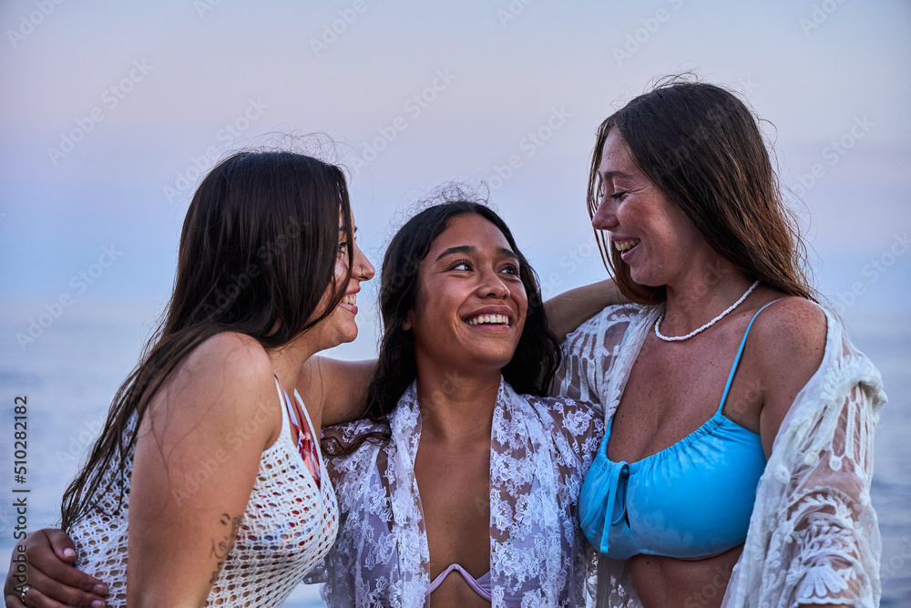group of three interracial friends enjoying each other's company on the beach on a summer afternoon. group of three interracial friends enjoying each other's company on the beach on a summer afternoon.