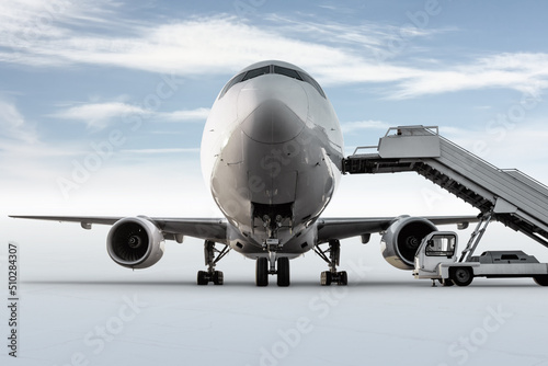 Close-up front view of passenger airliner and boarding stairs isolated on bright background with sky