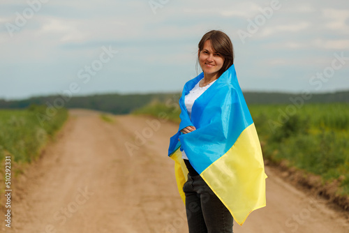 Woman with Ukrainian flag in wheat field. © Ruslan Ivantsov