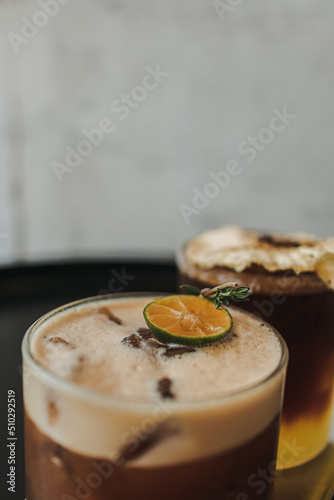 Two iced yusu orange coffee special drinks served on black table in the cafe. photo