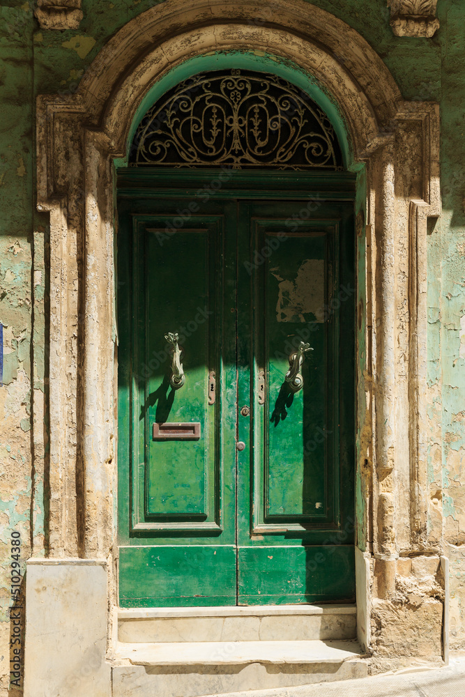 dilapidated shabby green door on an old building. Fish-shaped door handles