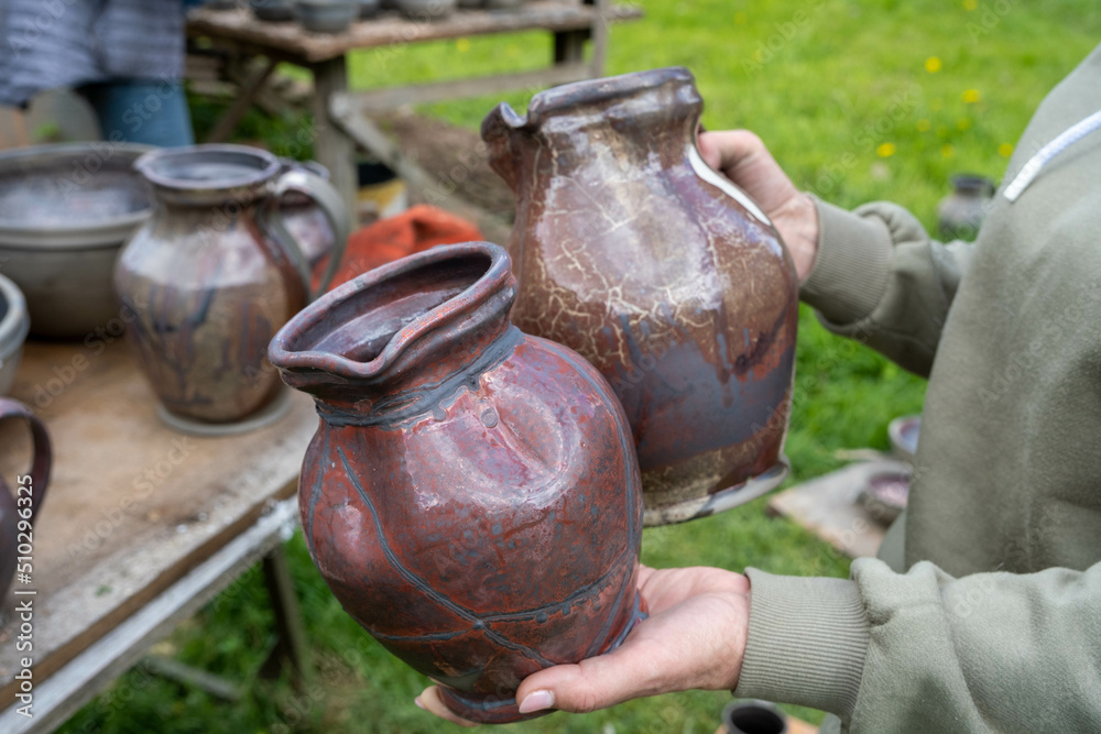 fired earthenware removed from the kiln. The woman looks at the outcome. Mugs, pots, plates and everything else beautiful and useful. Latvian national cultural heritage fired earthenware removed from the kiln. The woman looks at the outcome. Mugs, pots, plates and everything else beautiful and useful. Latvian national cultural heritage