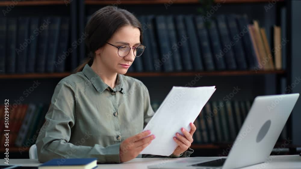 Modern business woman working with paper document and laptop at library desk Modern business woman working with paper document and laptop at library desk