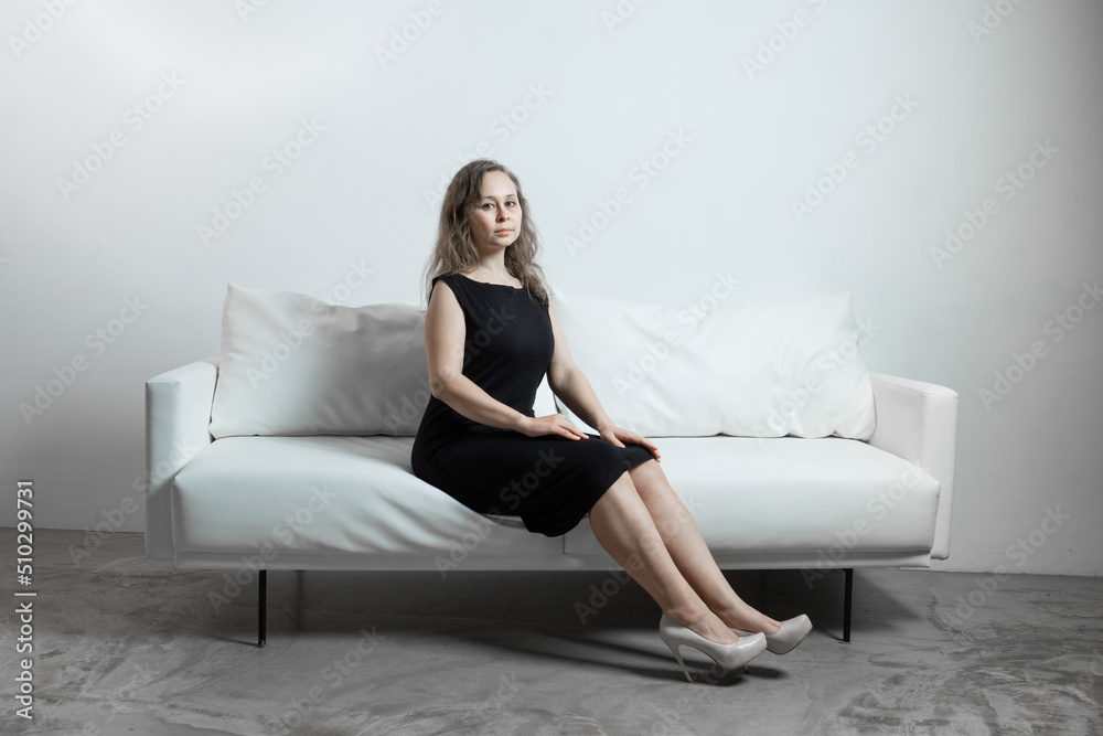 a girl in black dress sitting on a white leather sofa