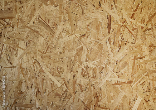 OSB boards are made of brown wood chips, sanded into a wooden background. Top view of OSB wood veneer, dense, seamless surfaces.