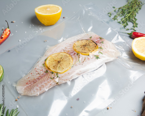 Vacuumed white fish on a gray background with lemon