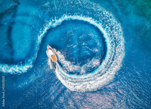 Aerial view of the speed boat in clear blue water at sunset in summer. Top view from drone of fast floating yacht in mediterranean sea. Travel in Oludeniz, Turkey. Tropical landscape with motorboat © den-belitsky