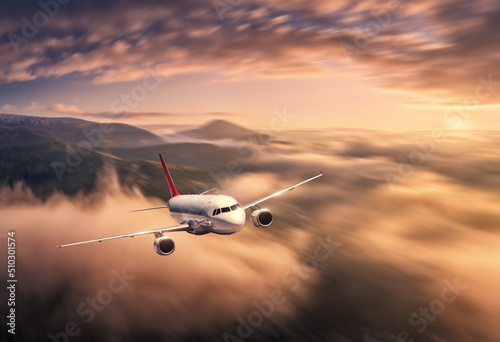 Airplane is flying above the clouds at sunset in summer. Landscape with passenger airplane, blurred background. Aircraft is taking off. Business travel. Commercial plane. Aerial view. Transport 