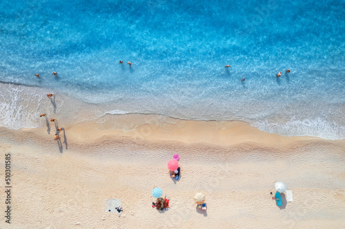 Canvas Print Aerial view of adriatic sea, waves, sandy beach and umbrellas with lying people at sunset in summer