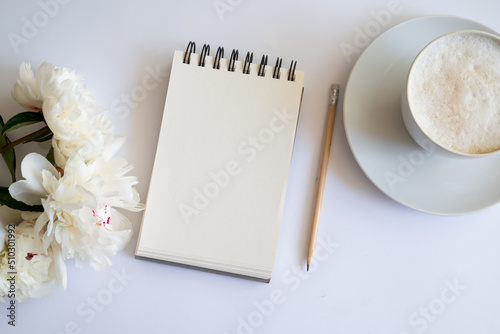 Top view of notebook with white empty page White peonies and Feminine home office mock up with blank sheet of paper A4 portrait format,copy space for text. Flat lay