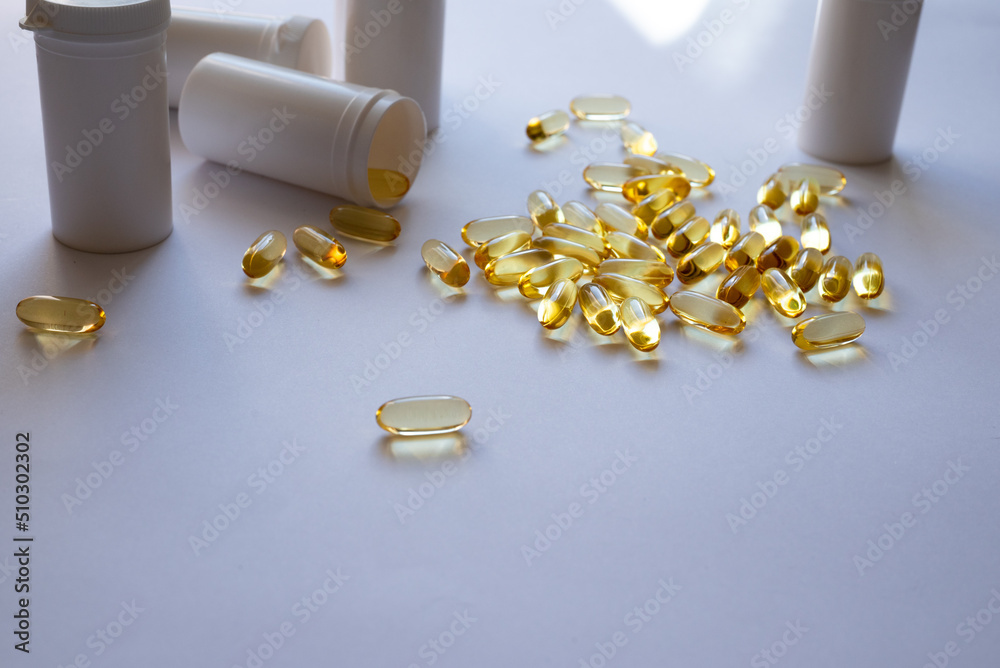 Yellow pills on white background, pill packings in the background. Lots of medication. Top view of Fish oil gel capsules isolated on white background. Salmon fish capsules view. Omega 3. Supplementary