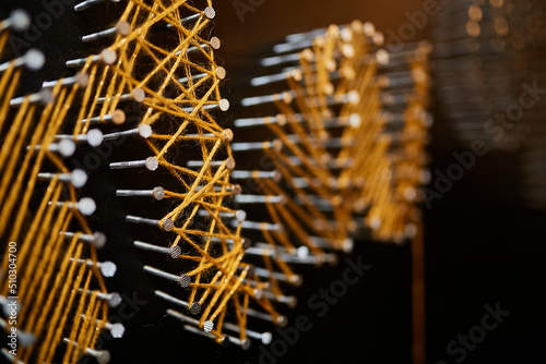 panel string art, yellow threads on nails close-up