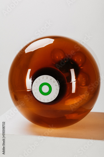brown plastic bottle of large size. empty canister lying on its side with cap screwed on. white background.