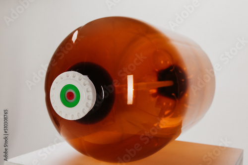 brown plastic bottle of large size. empty canister lying on its side with cap screwed on. white background