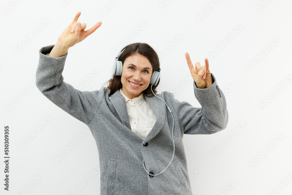 funny funny woman in stylish coat and headphones enjoying music gesturing signs of approval while standing on a light background with empty space funny funny woman in stylish coat and headphones enjoying music gesturing signs of approval while standing on a light background with empty space