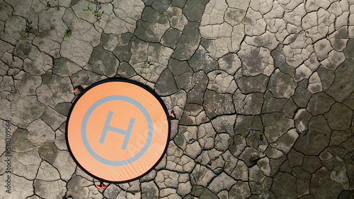 The quadcopter landing pad is on the ground. The soil is covered with cracked crust. Aerial photography. photo