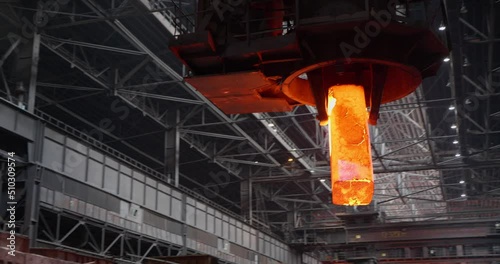 The crane gives out a mold of molten steel and puts it on a trolley for transportation. Metallurgical plant. Rolling shop. Business concept, modern steel production technology.
