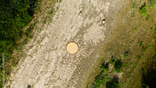 The quadcopter landing pad is on the ground. The soil is covered with cracked crust. Aerial photography. photo