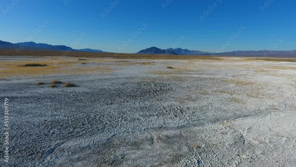 Pan up from white sandy desert with distant Death Valley mountains Pan up from white sandy desert with distant Death Valley mountains