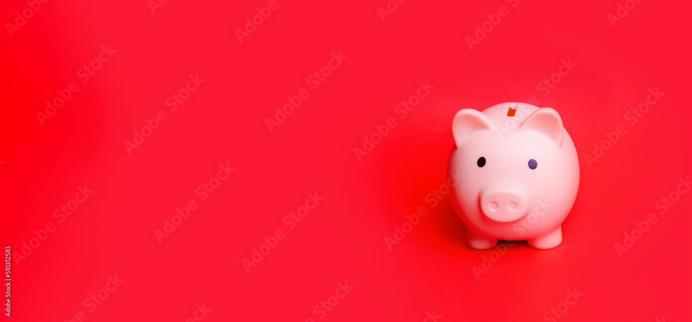Pink piggy bank isolated against red background Pink piggy bank isolated against red background