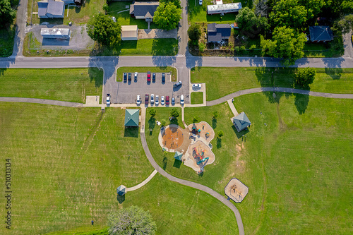 Fototapeta Naklejka Na Ścianę i Meble -  An overhead view of a community park with a water park, grassy fields, a pavilion, a gazebo, a swingset, and a parking lot.