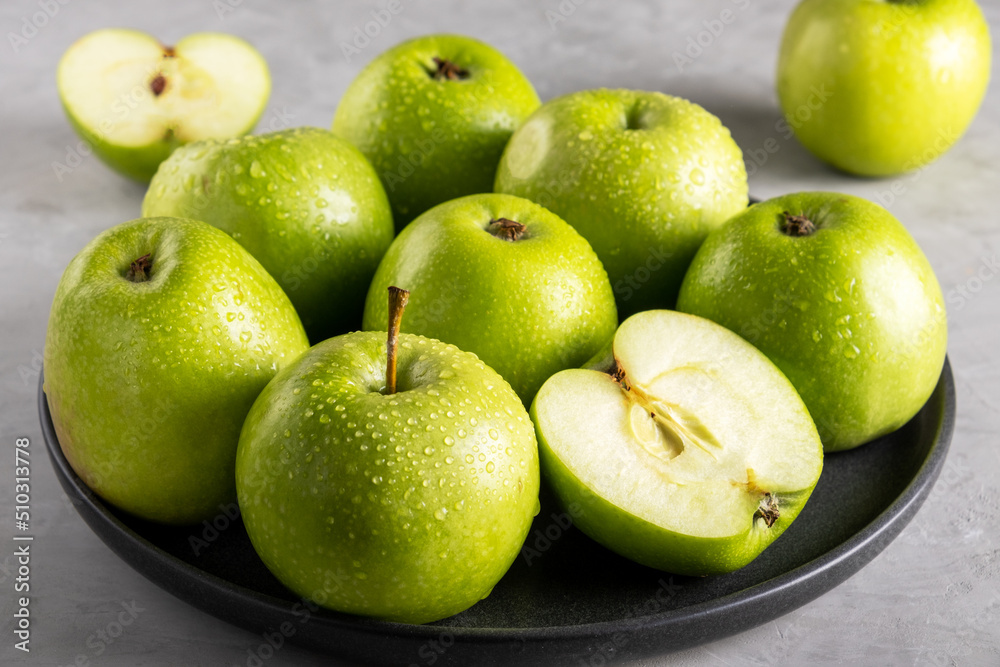 Fresh ripe green apples on a black ceramic plate on a gray background. Harvest, healthy food concept. Selective focus. Fresh ripe green apples on a black ceramic plate on a gray background. Harvest, healthy food concept. Selective focus.