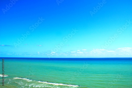 Fototapeta Naklejka Na Ścianę i Meble -  Beautiful view of the Adriatic Coast in Ortona with serene azure sky and colorful sea ranging from cyan to deep blue with pure white foam fuming behind rocks on a sunny summer day