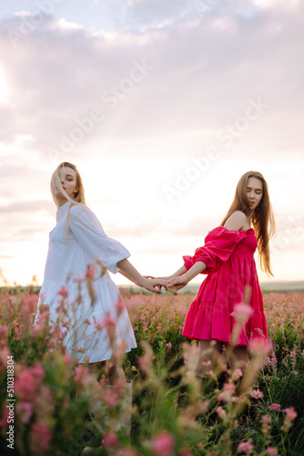 Two Beautiful woman in the blooming field. Fashion, style concept.