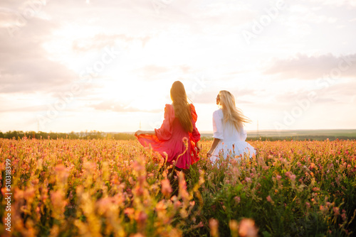 Two Beautiful woman in the blooming field. Fashion, style concept.