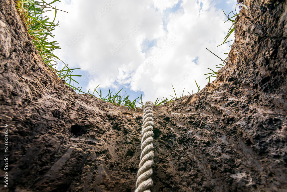 Fotografie Looking up from hole in ground with rope